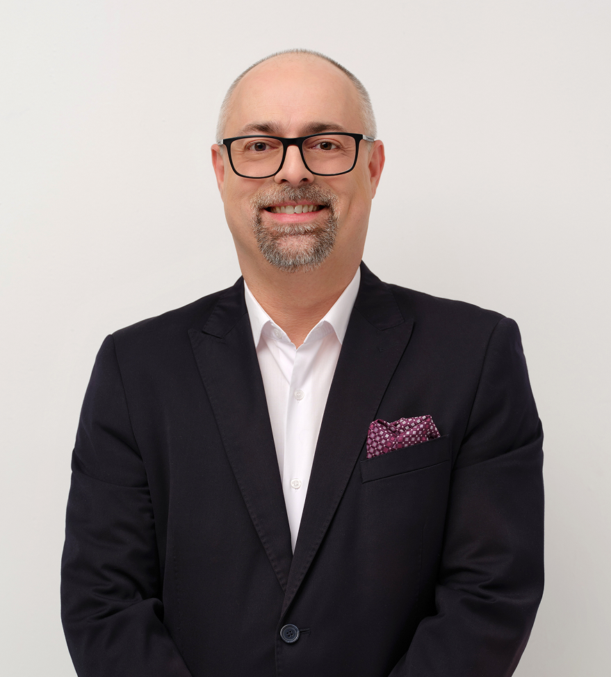 Mężczyzna w garniturze i okularach na białym tle.